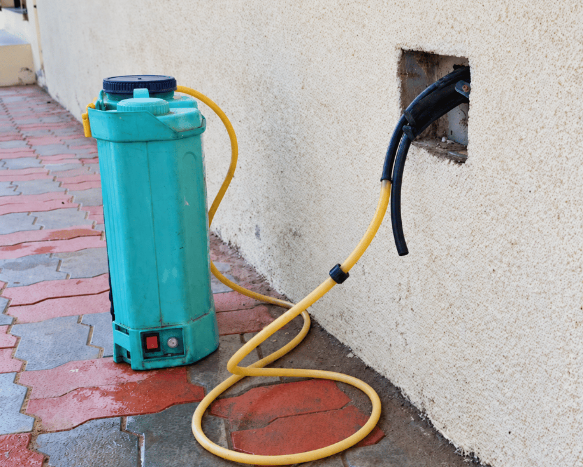 Technician injecting termiticide through a wall junction box